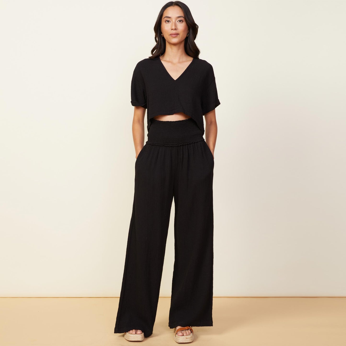 Front view of model wearing the gauze smocked flare pant in black.