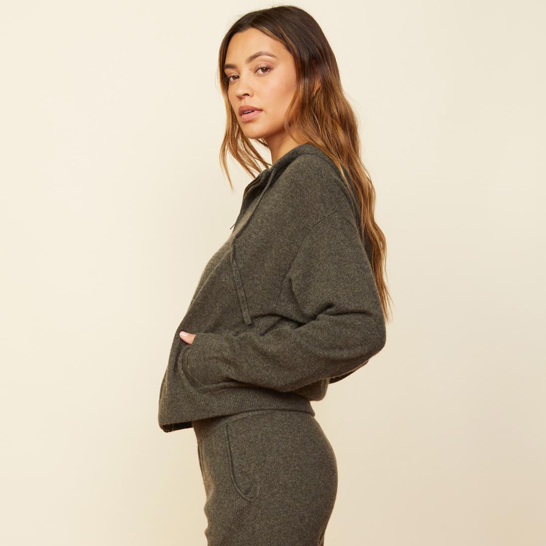 Side view of model wearing the cashmere zip up hoody in moss.