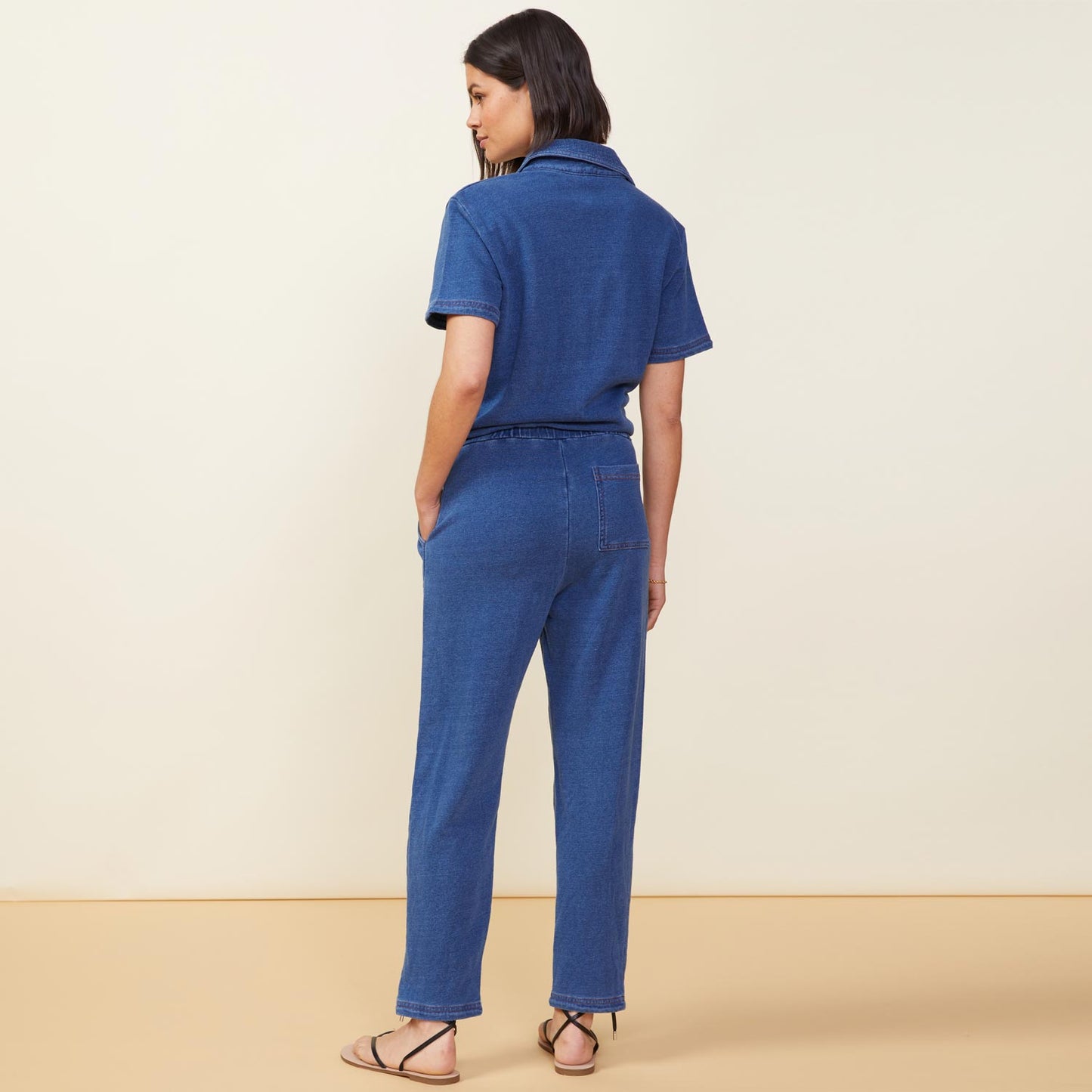 Back view of model wearing the indigo french terry jumpsuit in indigo.