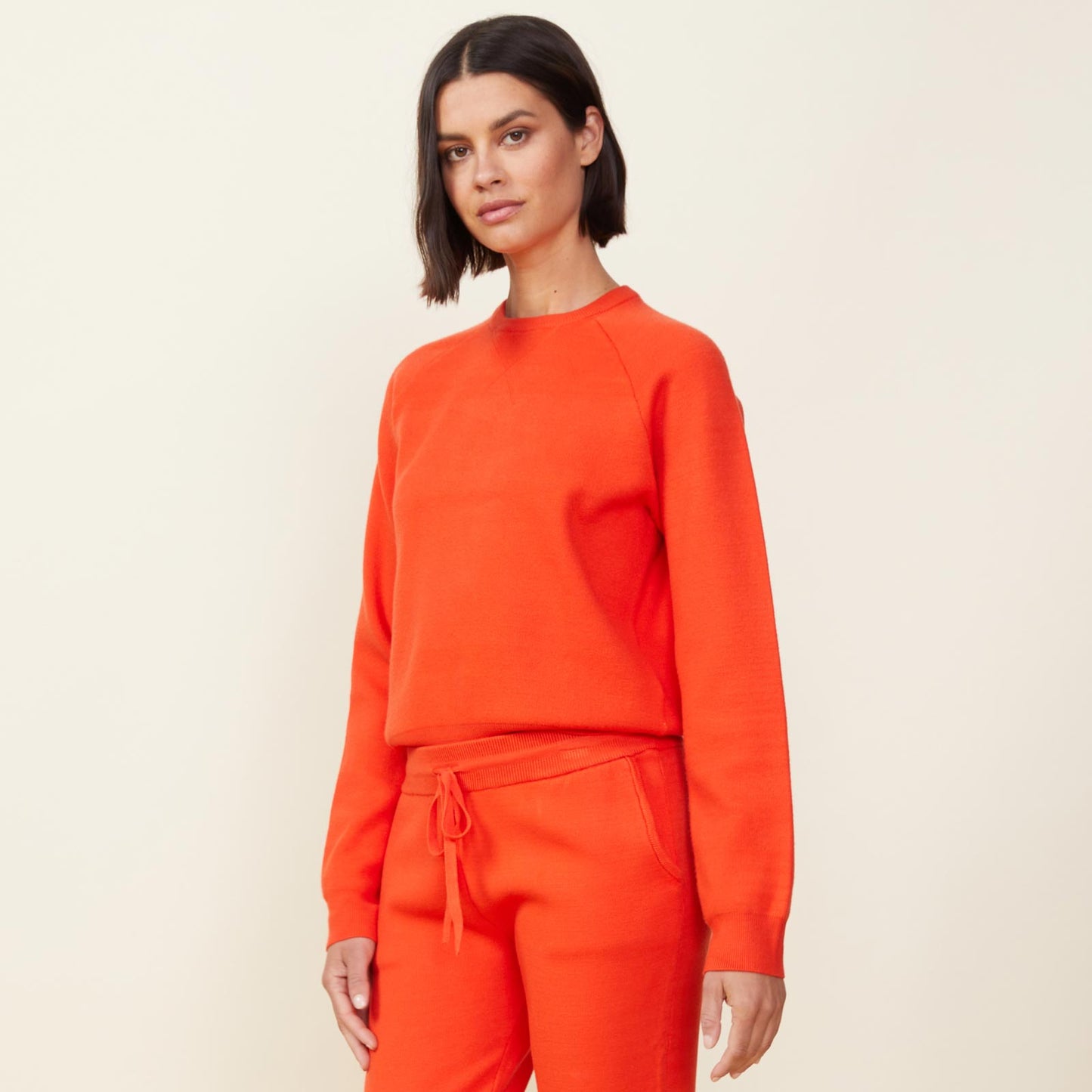 Side view of model wearing the supersoft sweater knit raglan in electric coral.