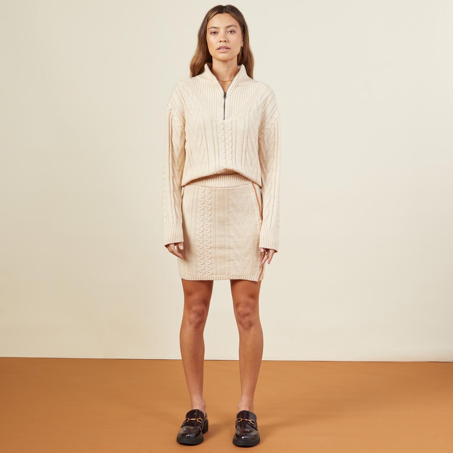 Front view of model wearing the merino cable knit half zip in off white.