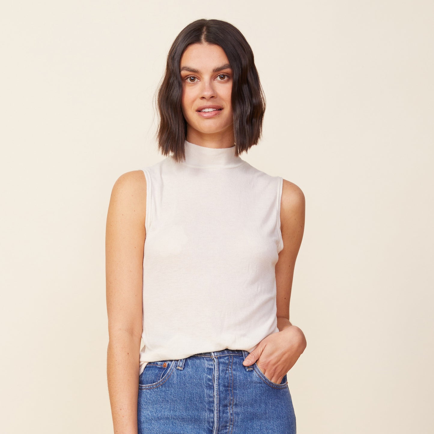 Front view of model wearing the light mock neck tank in off white.