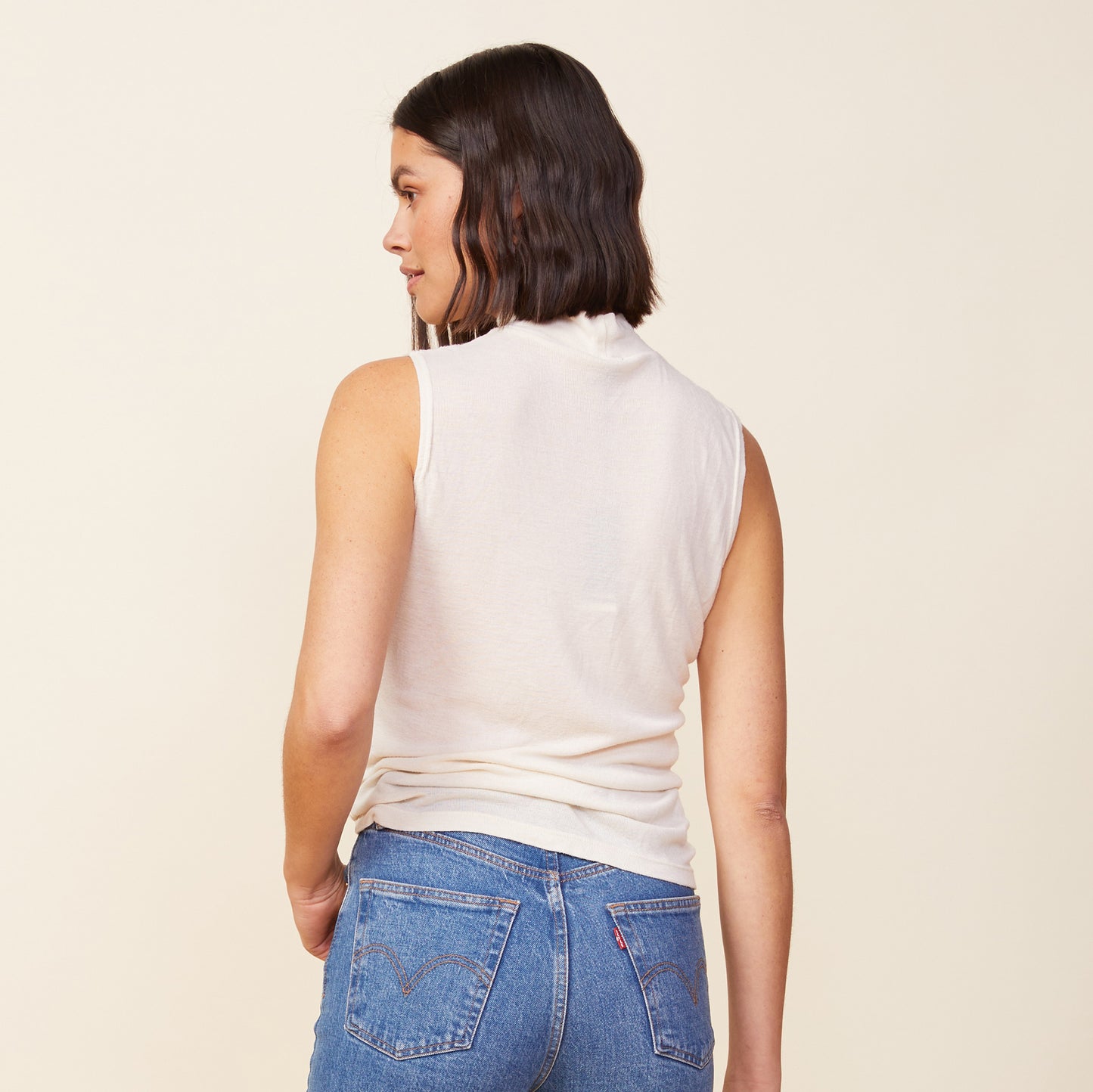 Back view of model wearing the light mock neck tank in off white.