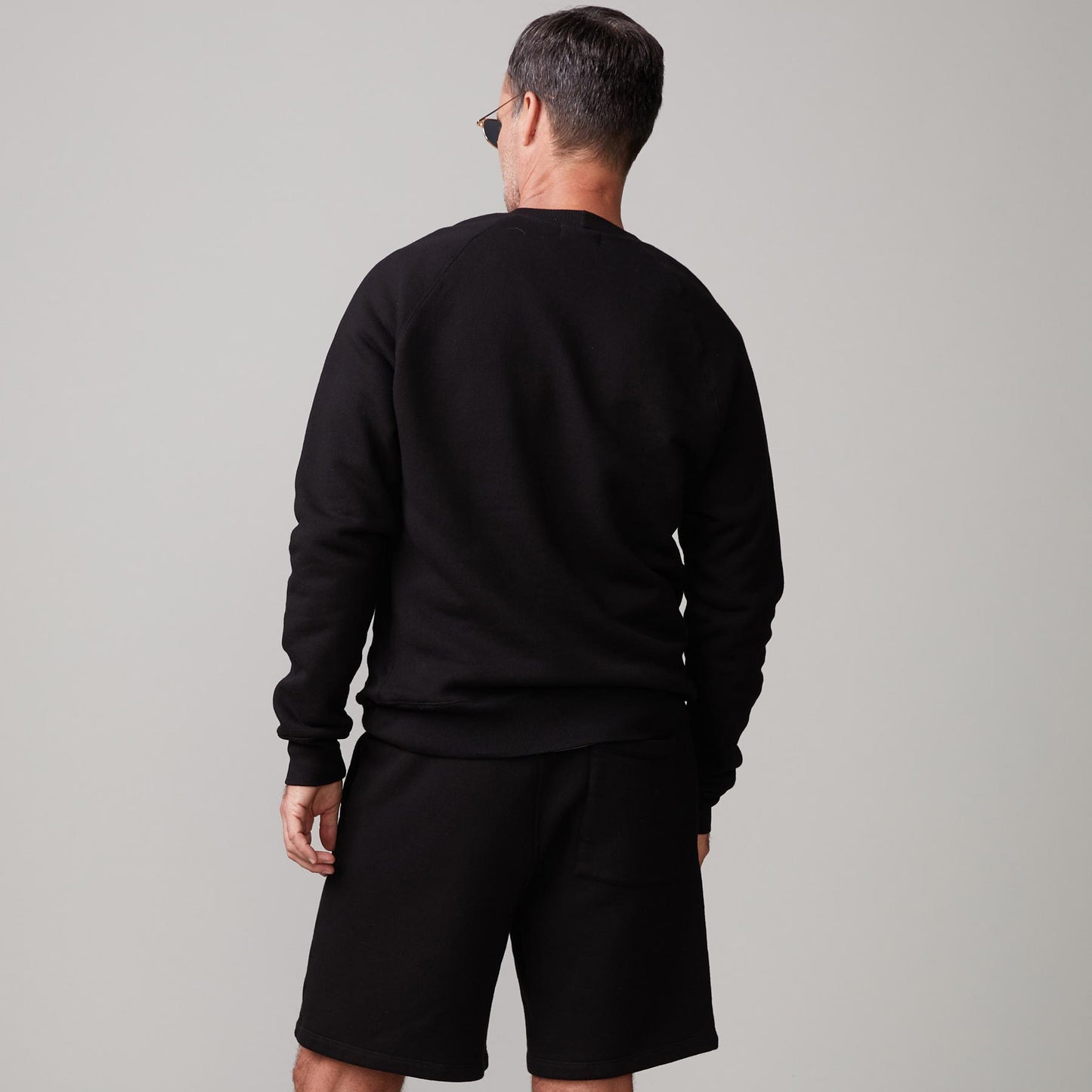 Back view of model wearing the 70's raglan in black.