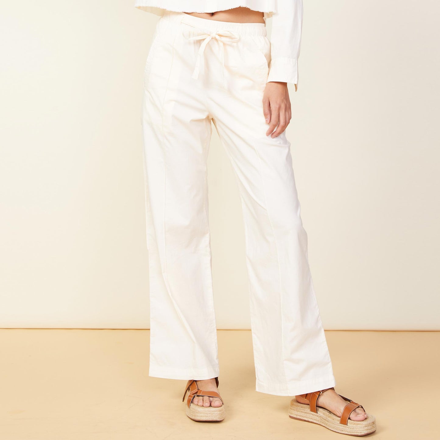 Front view of model wearing the poplin pocket pants in off white.