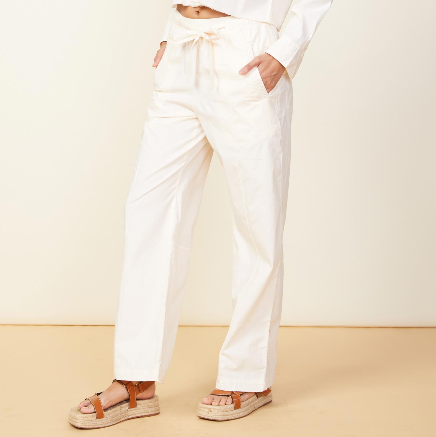 Side view of model wearing the poplin pocket pants in off white.