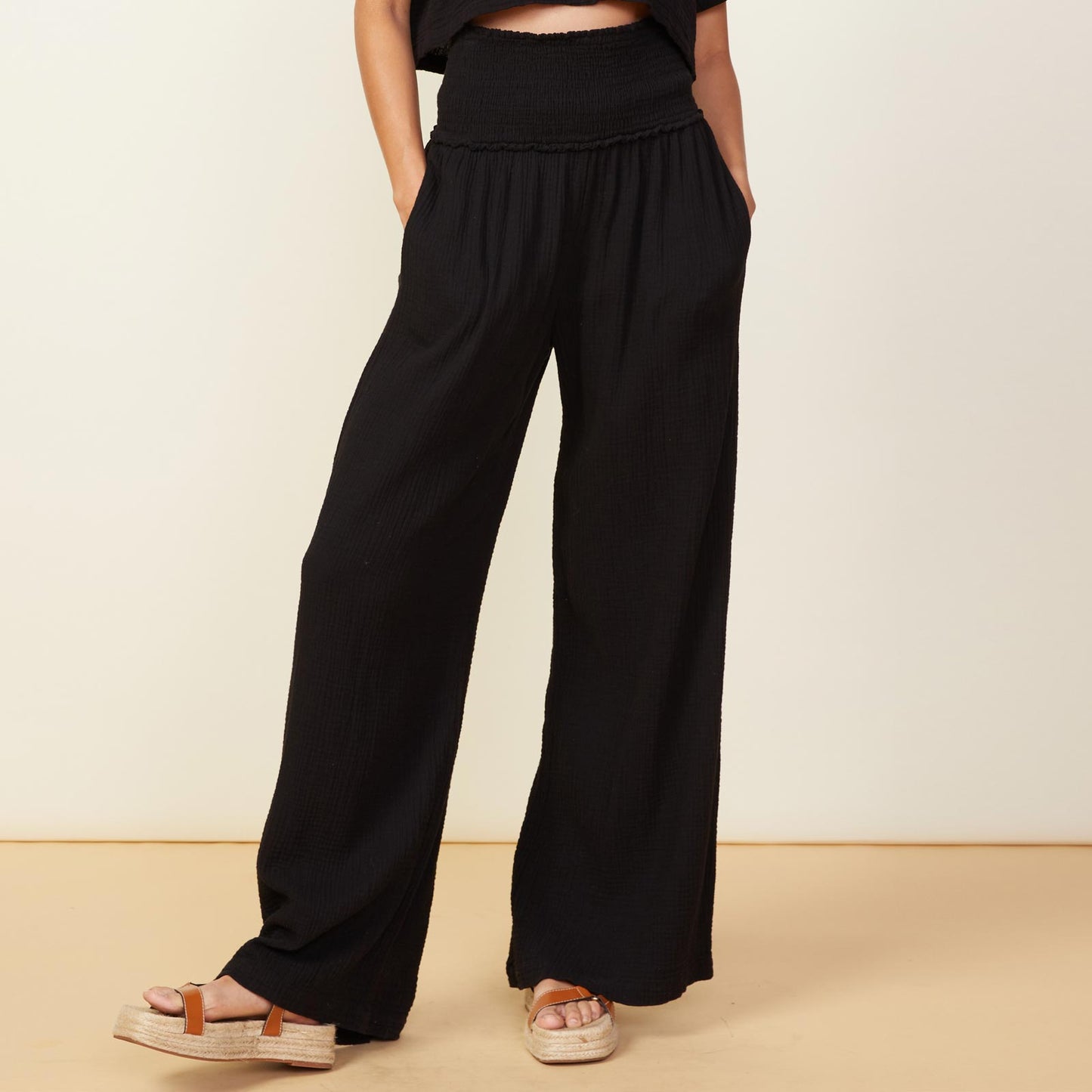 Front view of model wearing the gauze smocked flare pant in black.