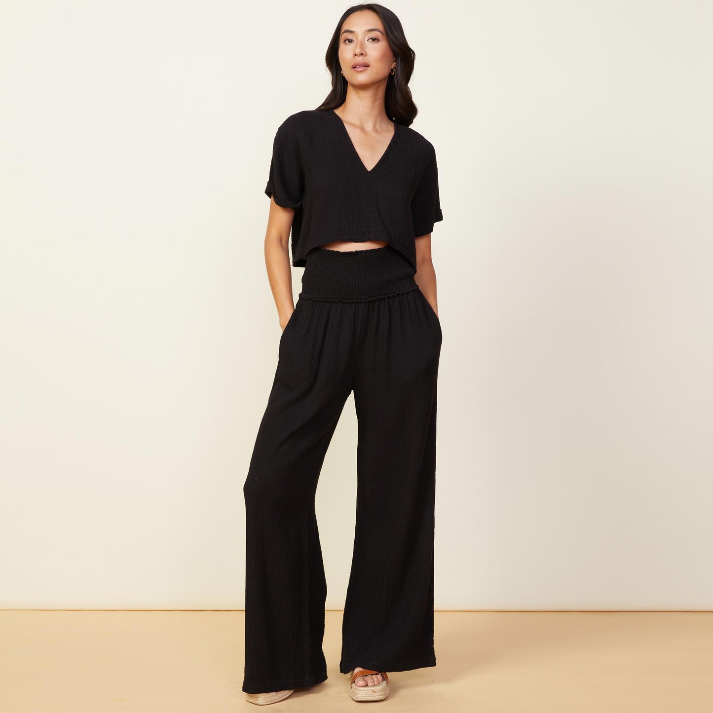 Front view of model wearing the gauze smocked flare pant in black.