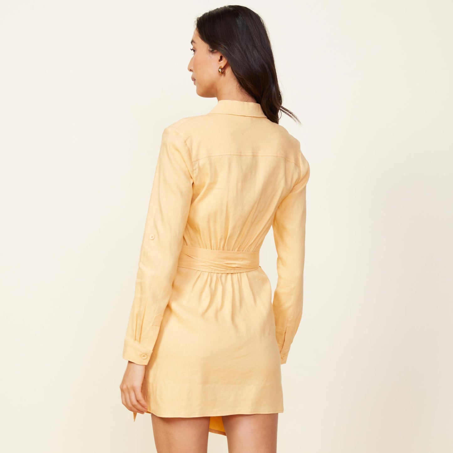 Back view of model wearing the linen mini dress in sand.