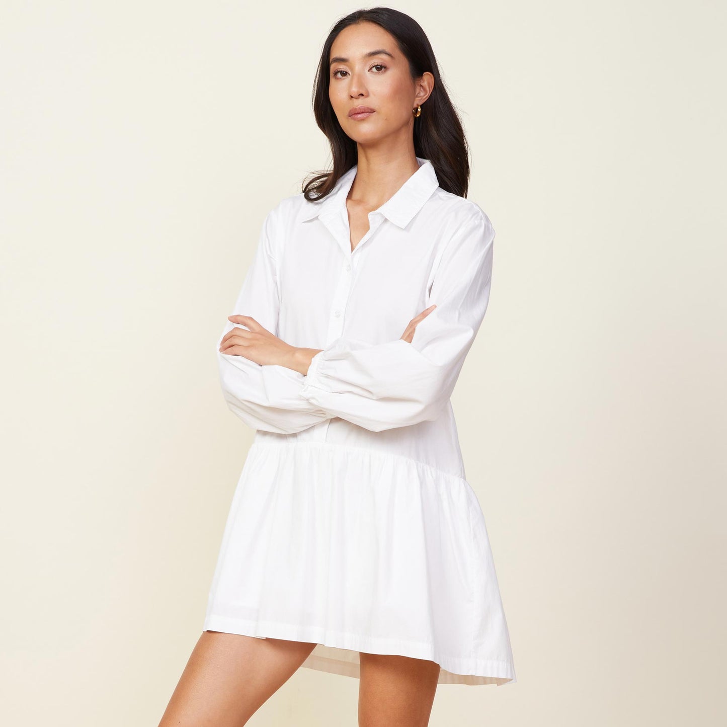 Side view of model wearing the poplin easy shirt dress in white.