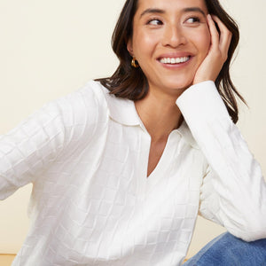 Close up view of model wearing the checkered polo sweater in white.