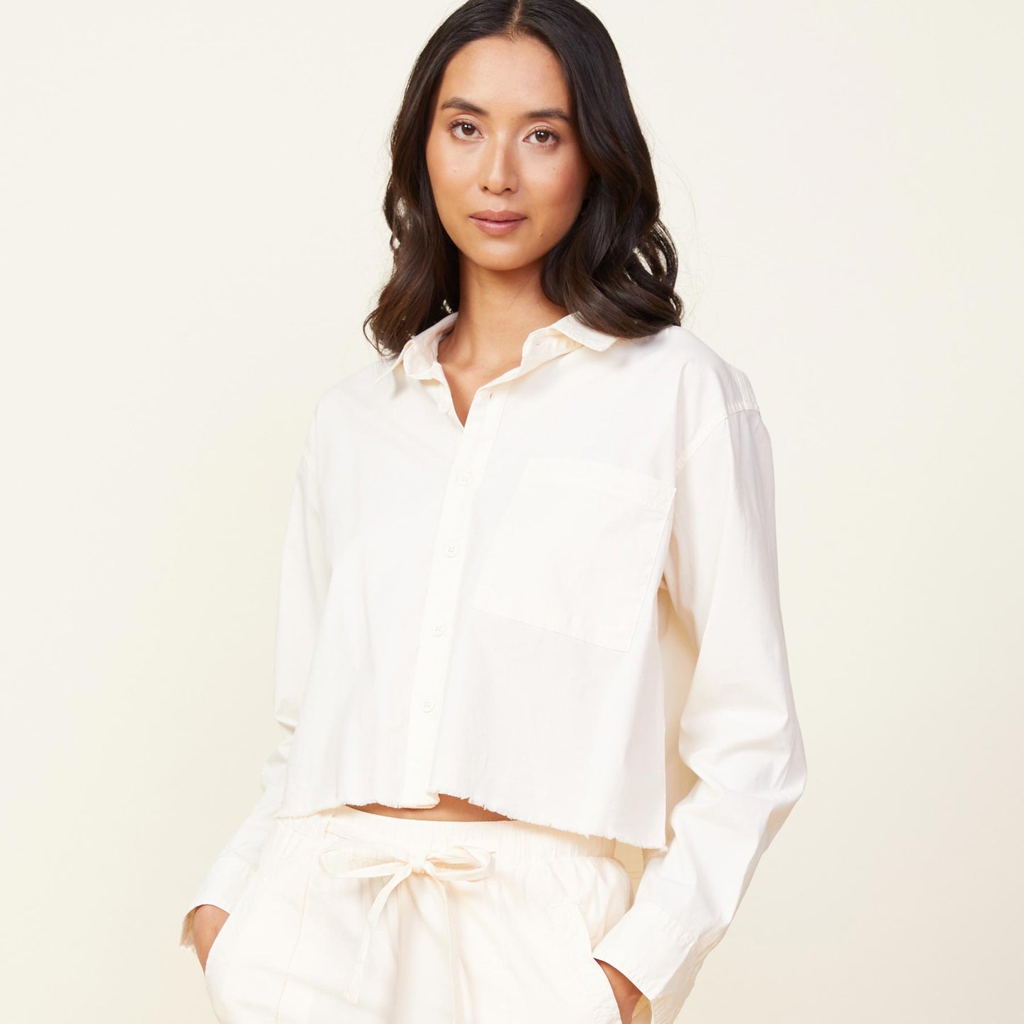 Front view of model wearing the cropped poplin shirt in off white.