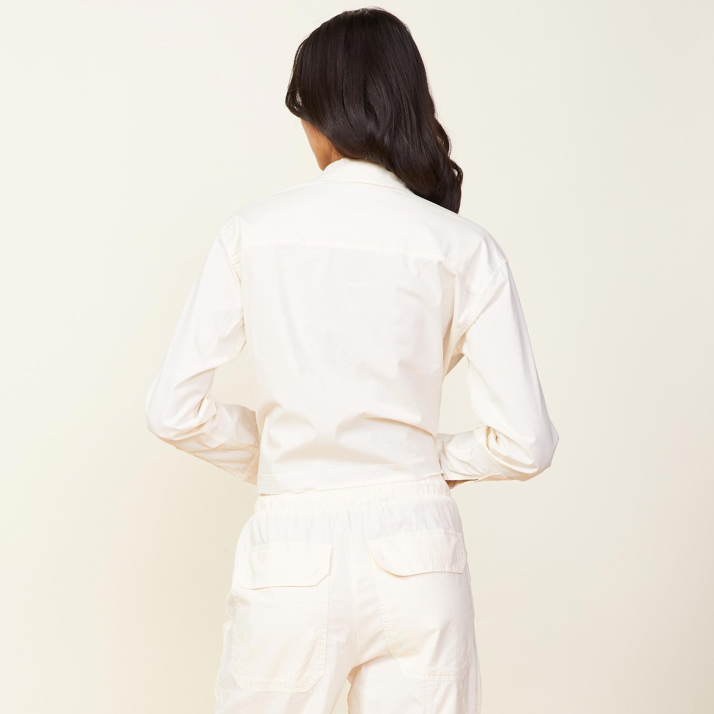Back view of model wearing the cropped poplin shirt in off white.