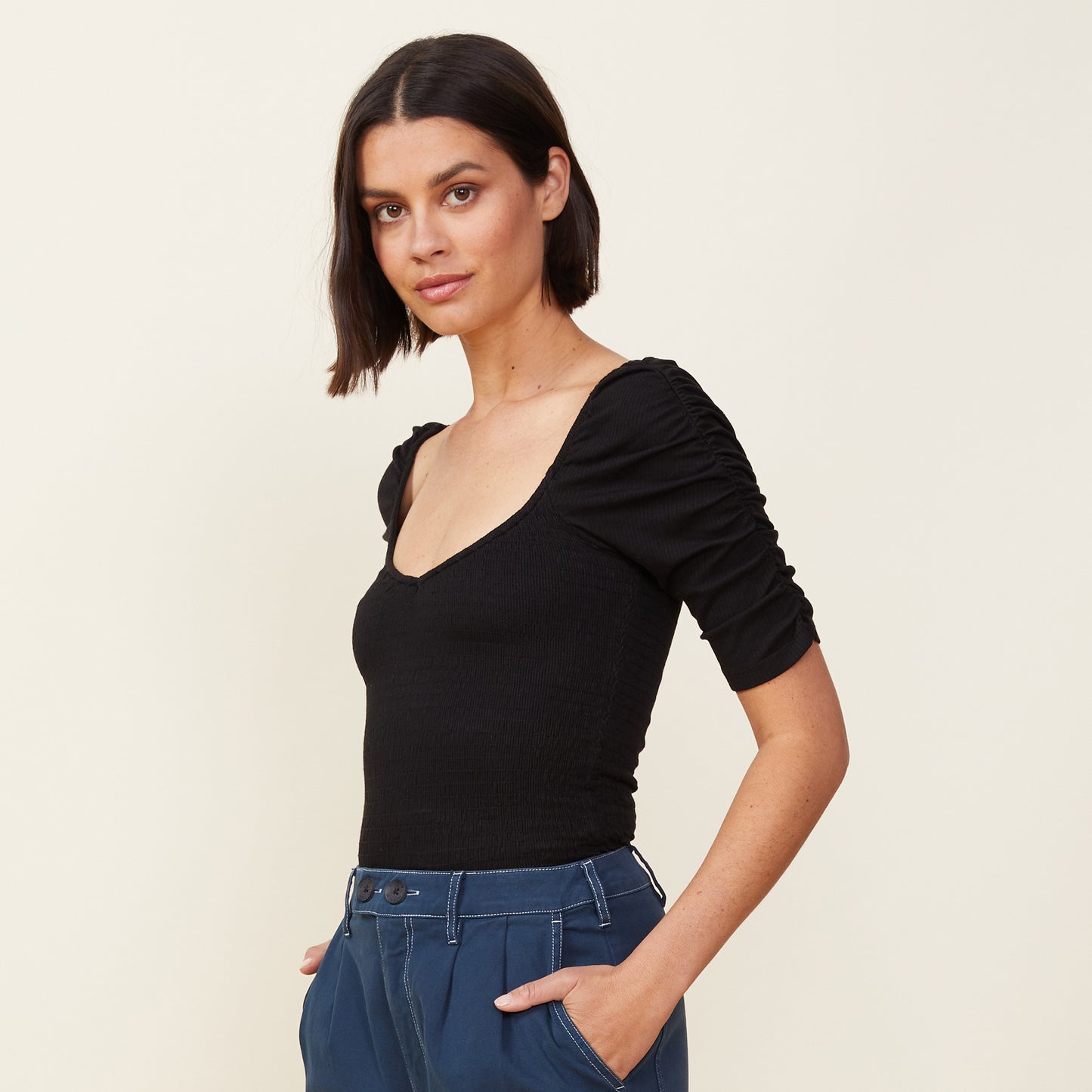Side view of model wearing the rib smocked top in black.
