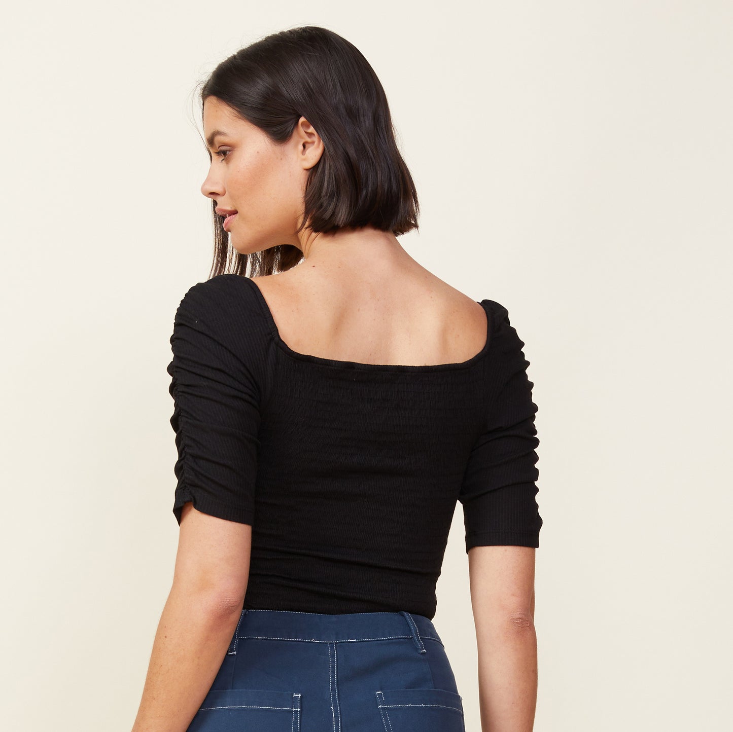 Back view of model wearing the rib smocked top in black.