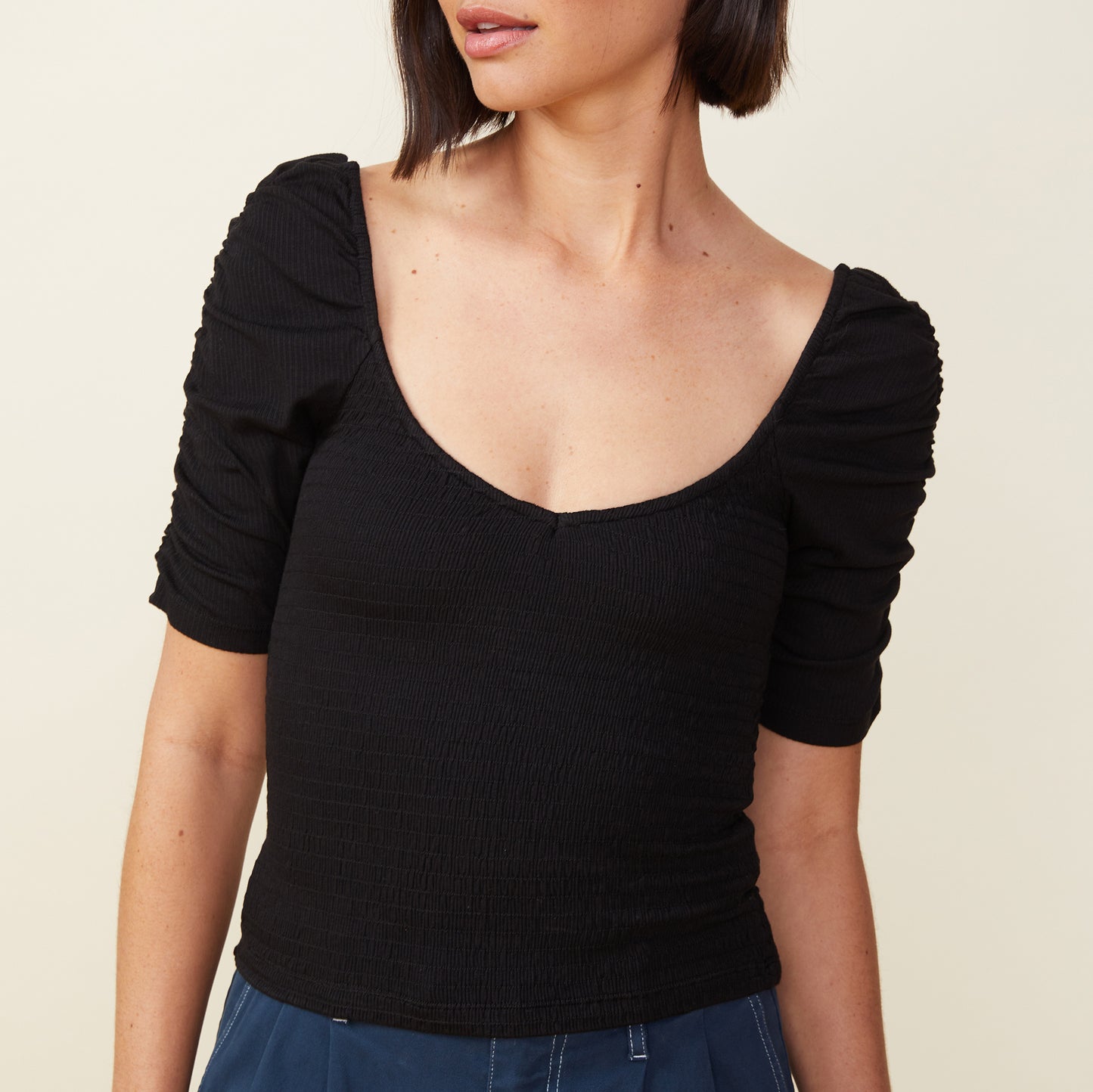 Front view of model wearing the rib smocked top in black.