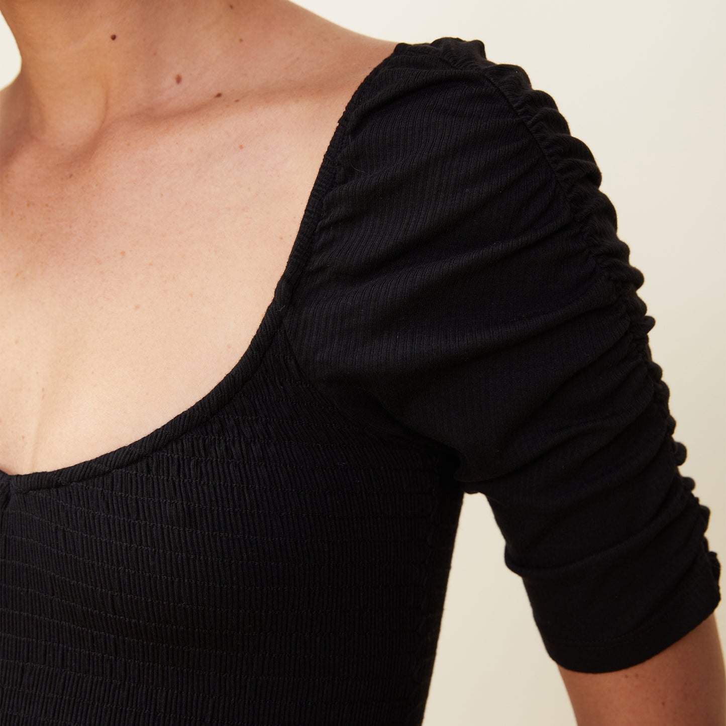 Close up view of model wearing the rib smocked top in black.
