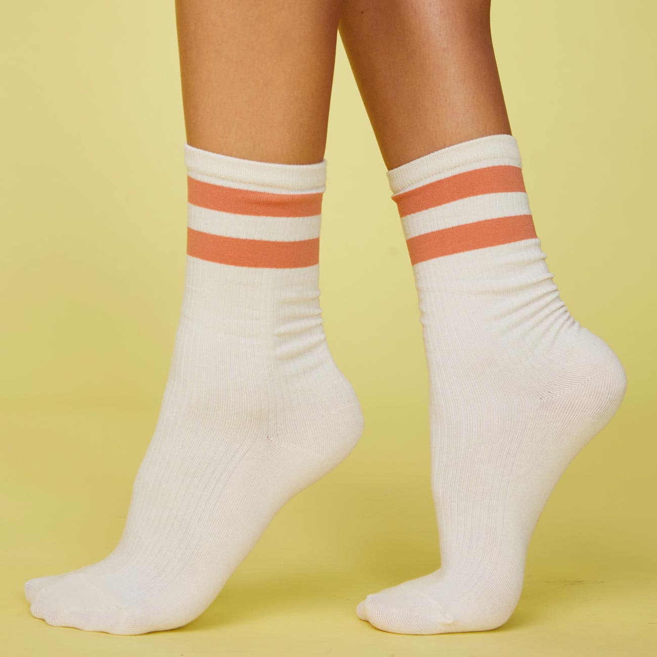 Side view of models feet wearing the stripe socks in faded rust.