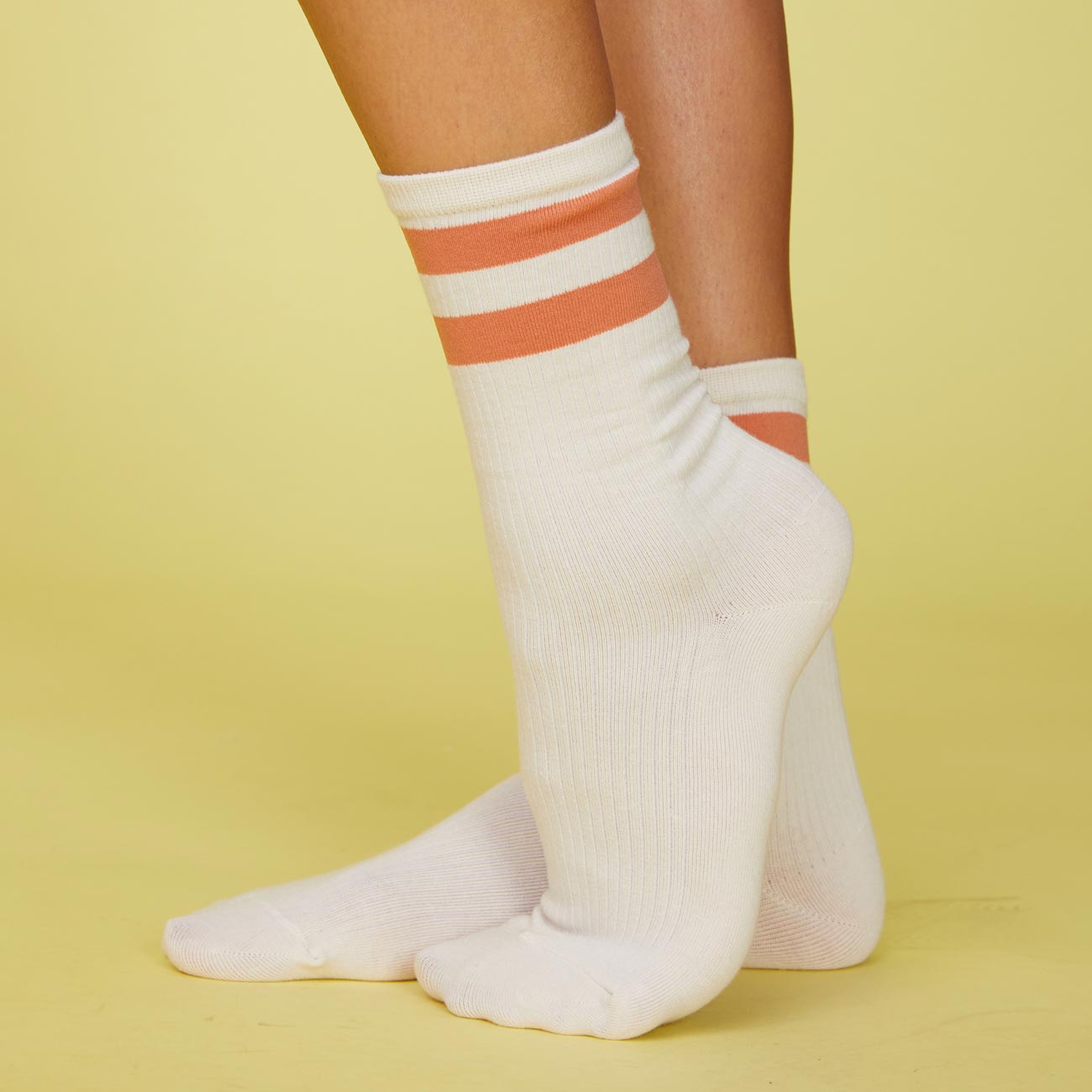 Side view of models feet wearing the stripe socks in faded rust.