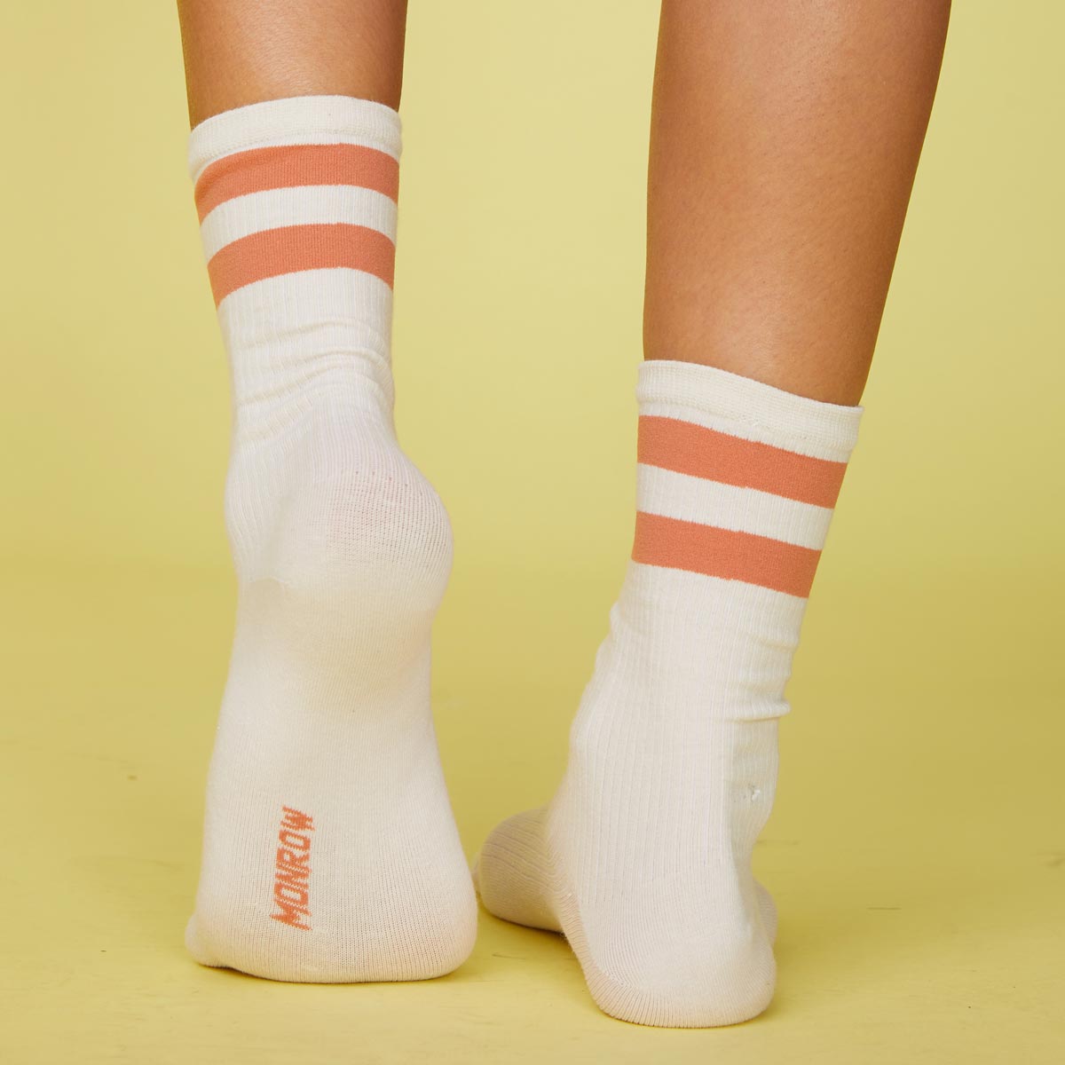 Back view of models feet wearing the stripe socks in faded rust.