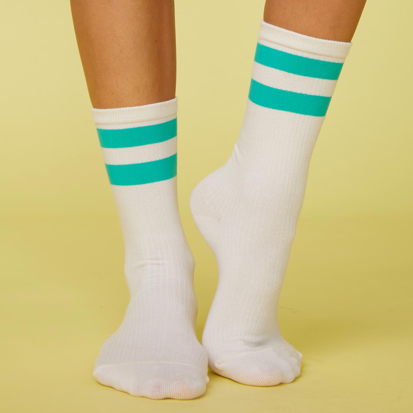 Front view of model's feet wearing the stripe socks in peacock green.