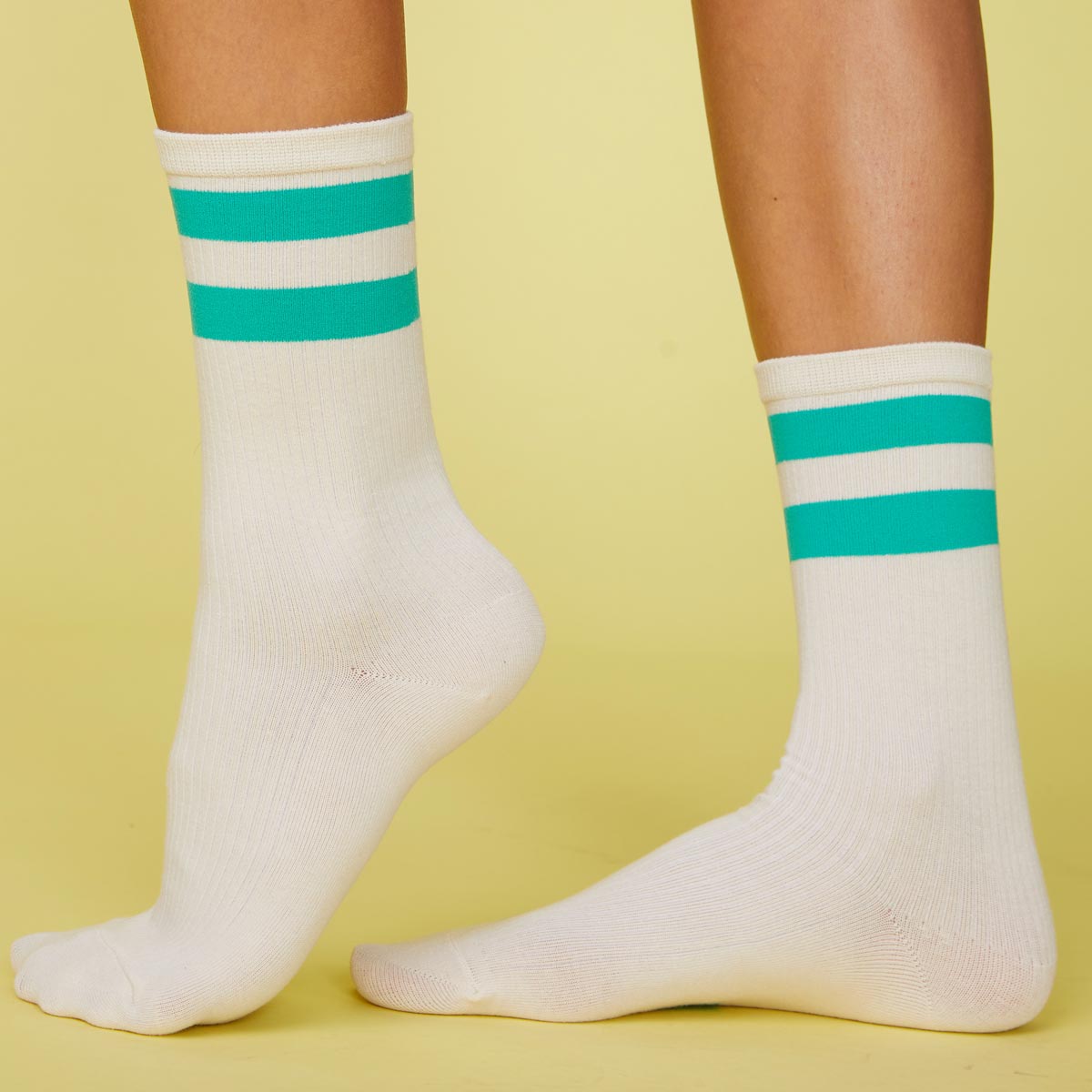 Side view of model's feet wearing the stripe socks in peacock green.