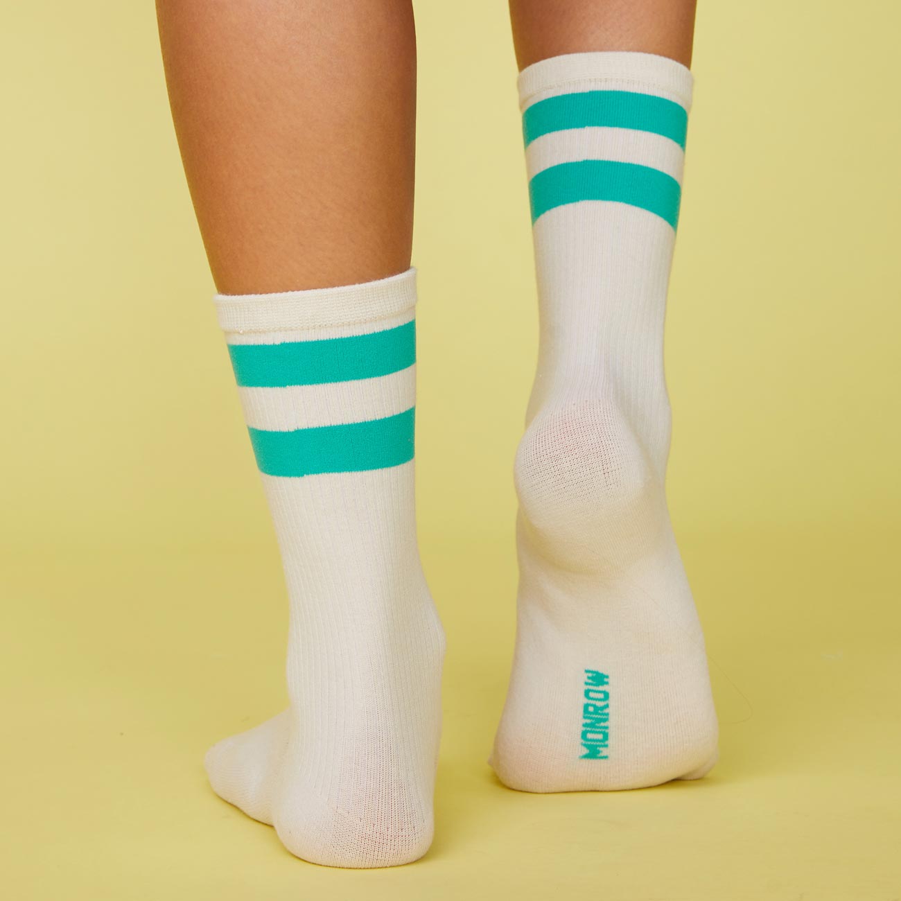 Back view of model's feet wearing the stripe socks in peacock green.