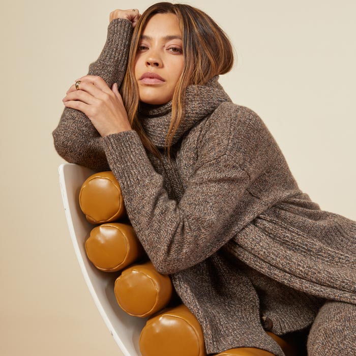 Front view of model sitting in the marled scarf in black sesame.