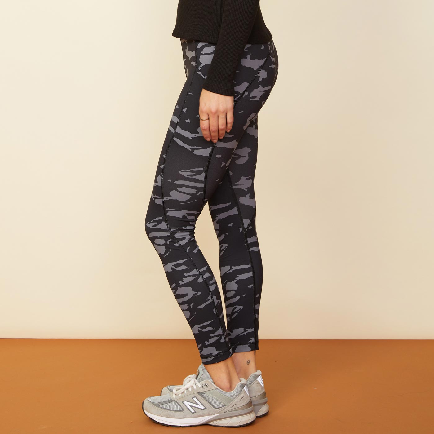 Side view of model wearing the two-tone camo movement high rise legging in vintage black.