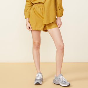 Front view of model wearing the poplin shorts in golden olive.