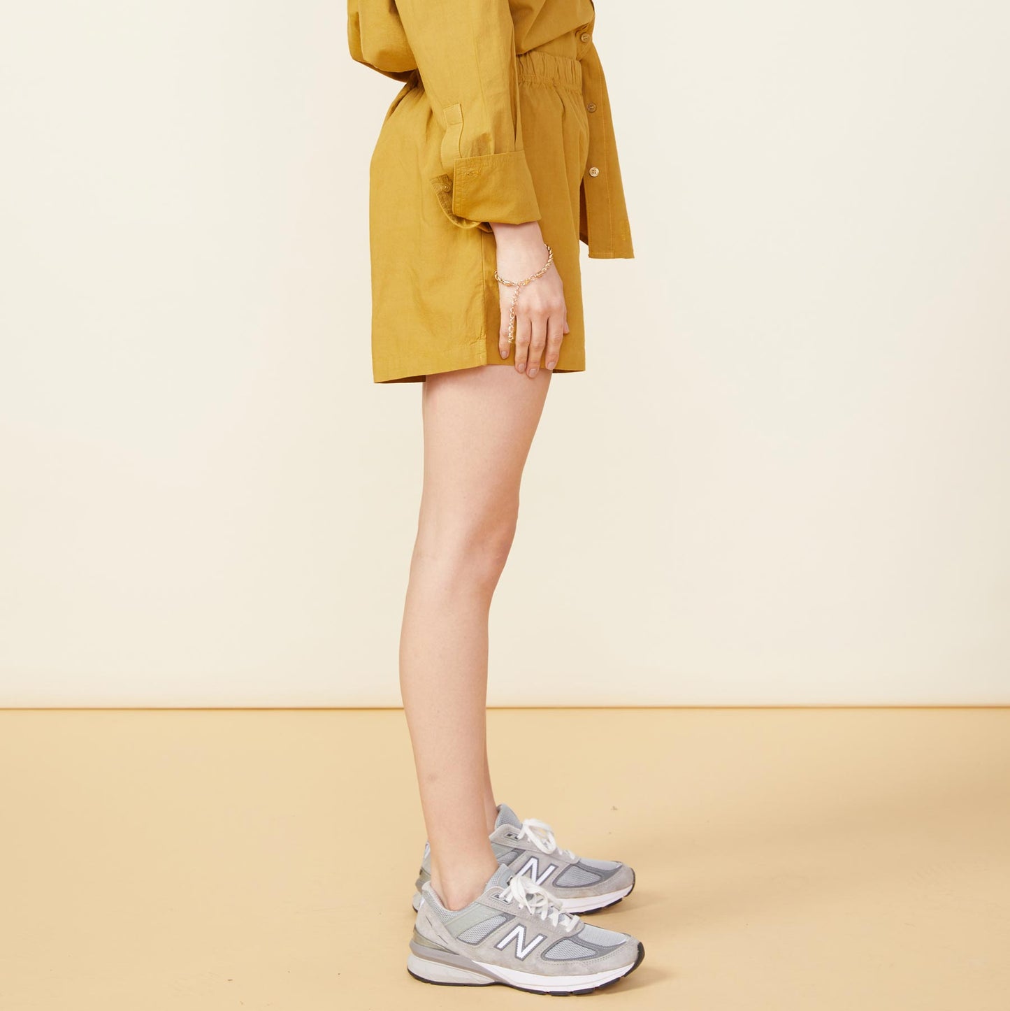 Side view of model wearing the poplin shorts in golden olive.