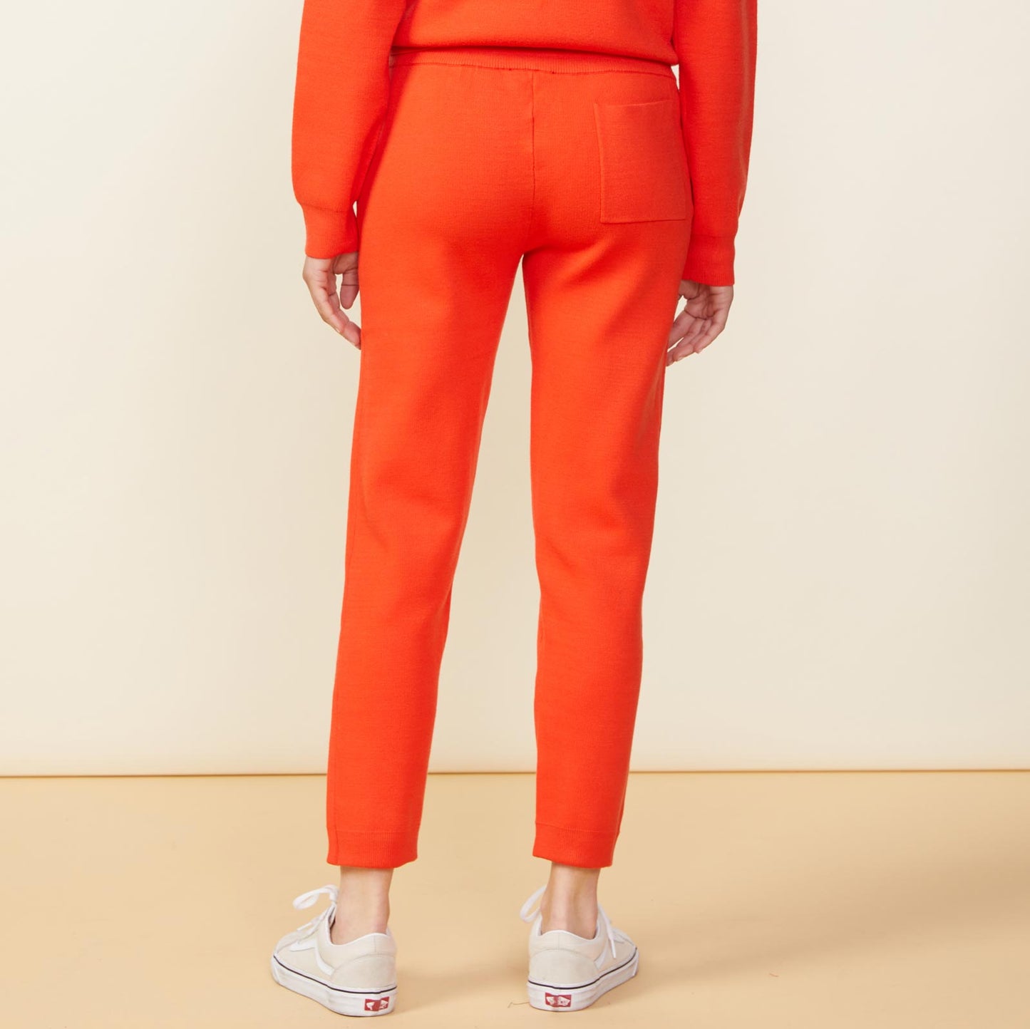 Back view of model wearing the supersoft sweater knit cuffed jogger in electric coral.
