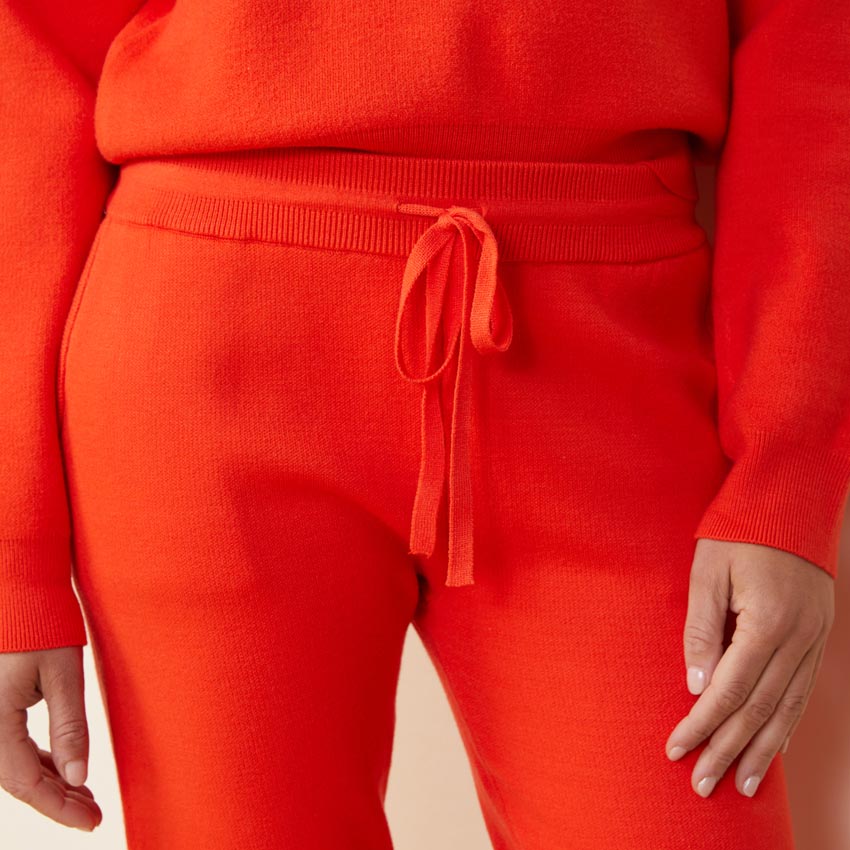 Close up view of model wearing the supersoft sweater knit cuffed jogger in electric coral.