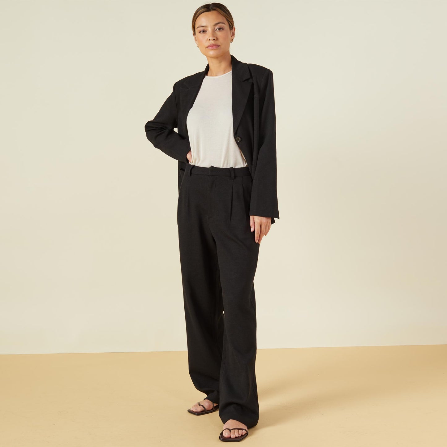 Front view of model wearing the bonded thermal pleated pants in black.