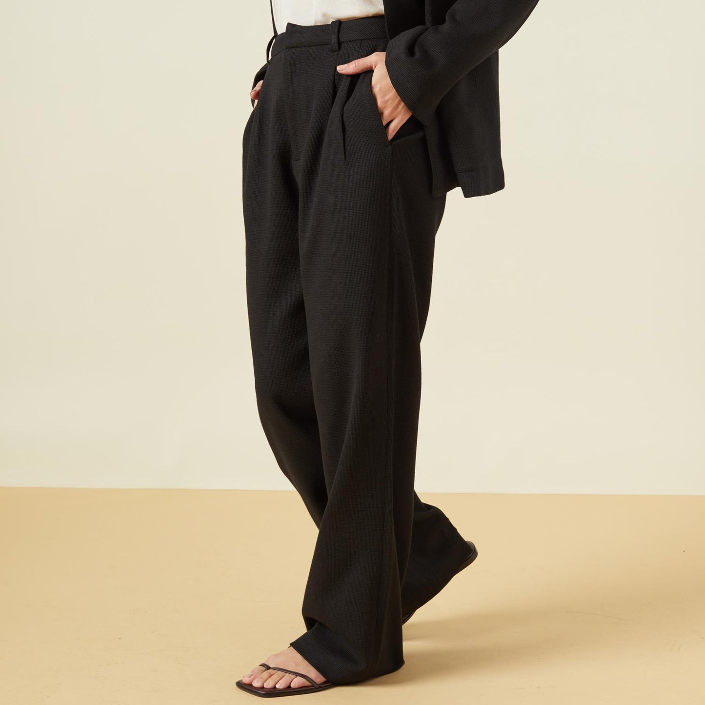 Side view of model wearing the bonded thermal pleated pants in black.