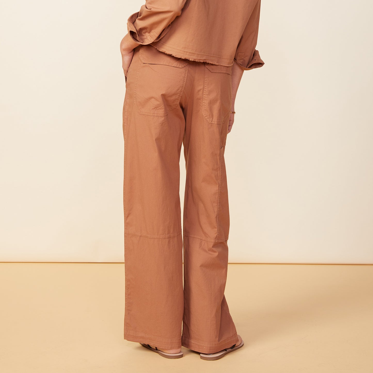 Back view of model wearing the poplin pocket pants in sahara.