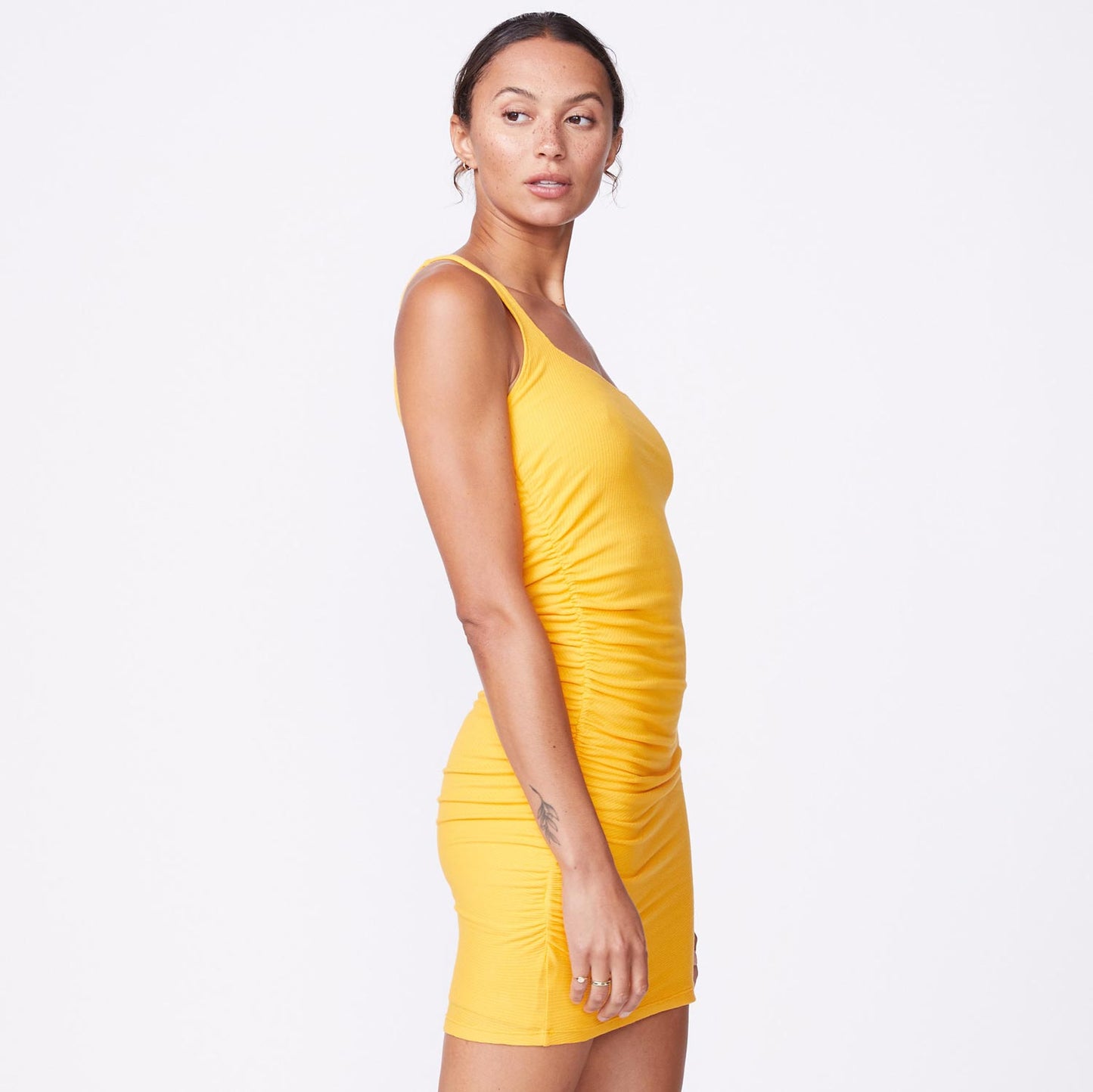 Side view of model wearing the rib square neck mini dress in marigold.