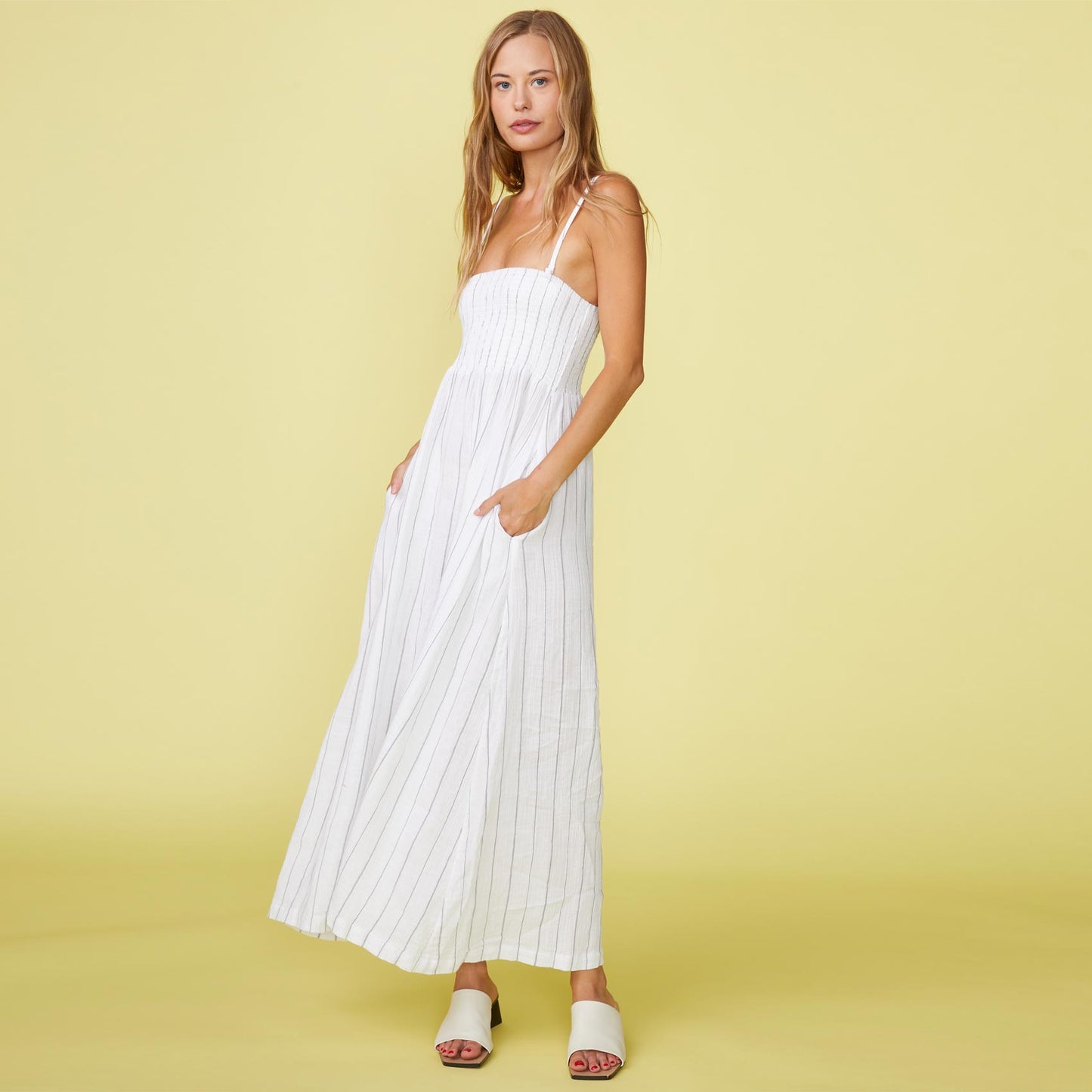 Front view of model wearing the pinstripe gauze smocked maxi dress in white.