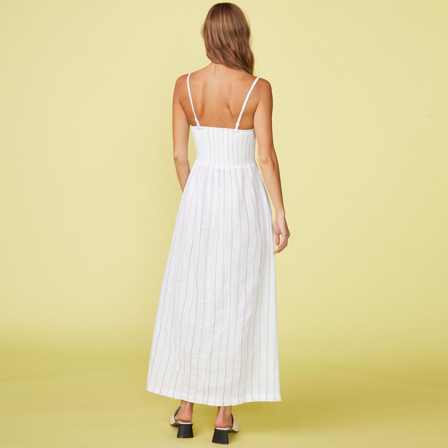 Back view of model wearing the pinstripe gauze smocked maxi dress in white.