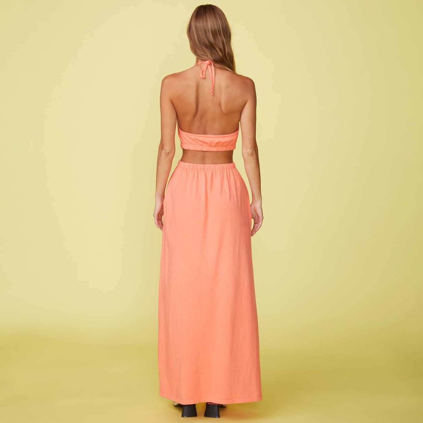 Back View of model wearing the Cut Out Halter Dress in Georgia Peach.