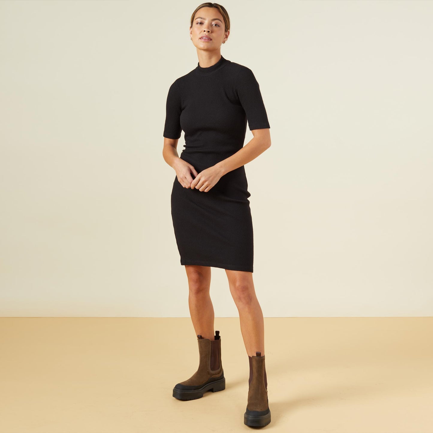 Front view of model wearing the brushed rib mock neck dress in black.