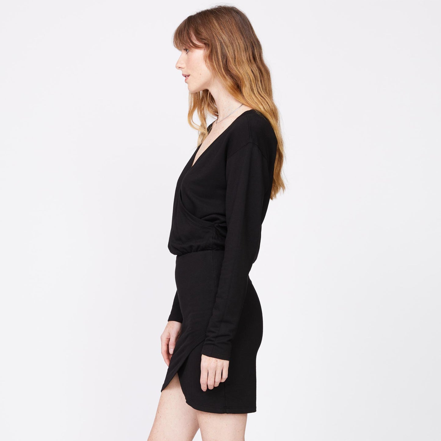 Side view of model wearing the supersoft fleece crossover v dress in black.