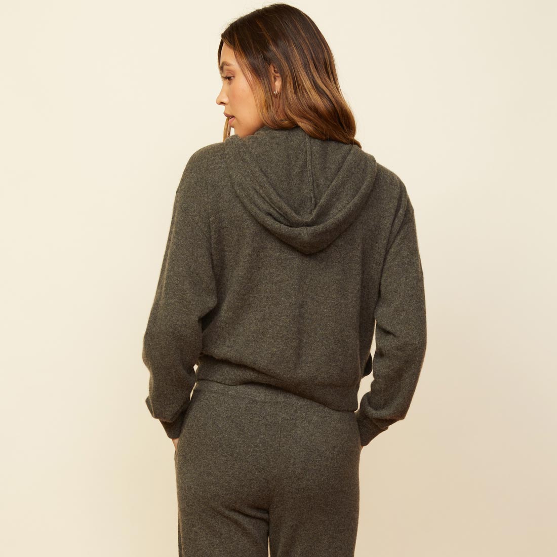 Back view of model wearing the cashmere zip up hoody in moss.