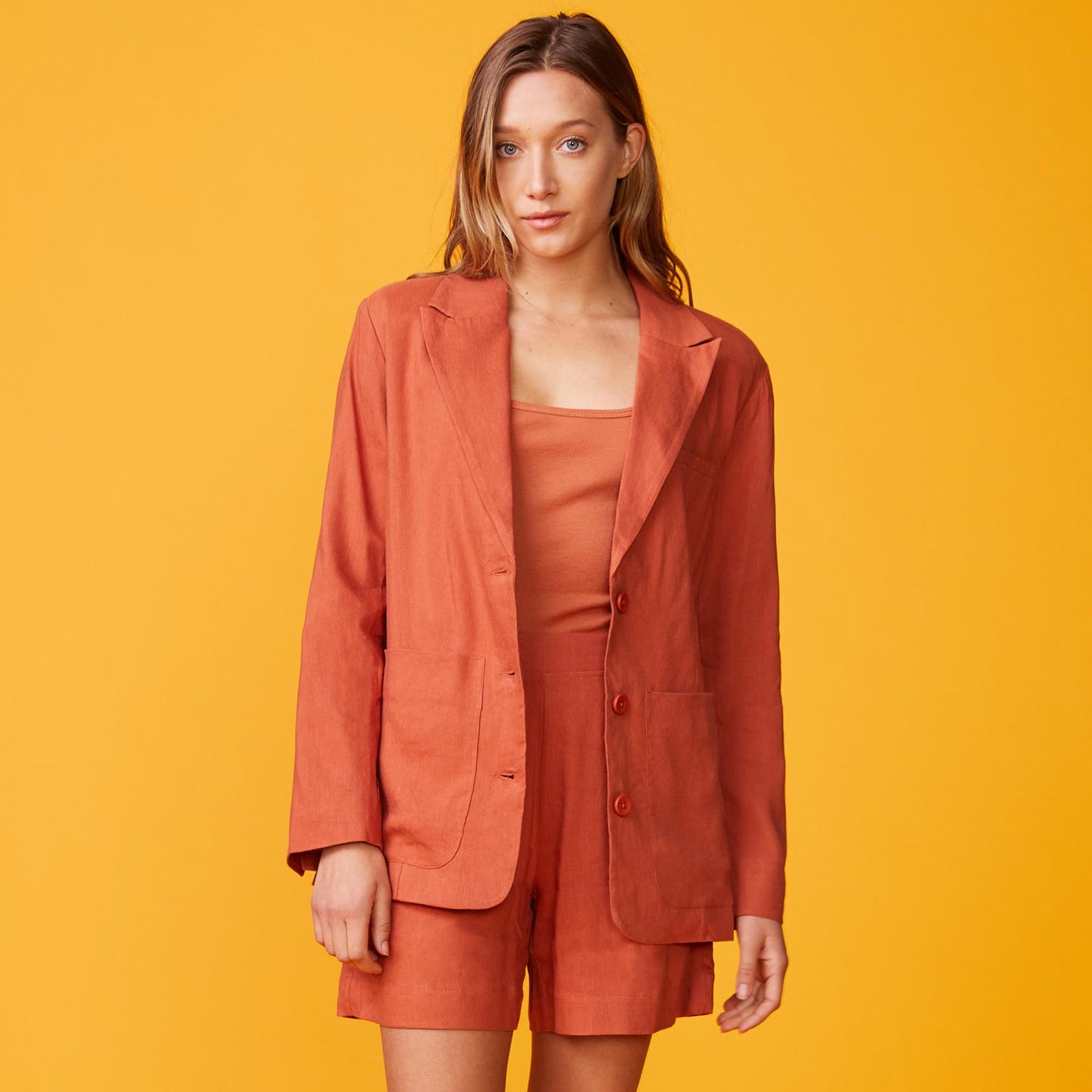 Front view of model wearing the linen oversized blazer in faded rust.