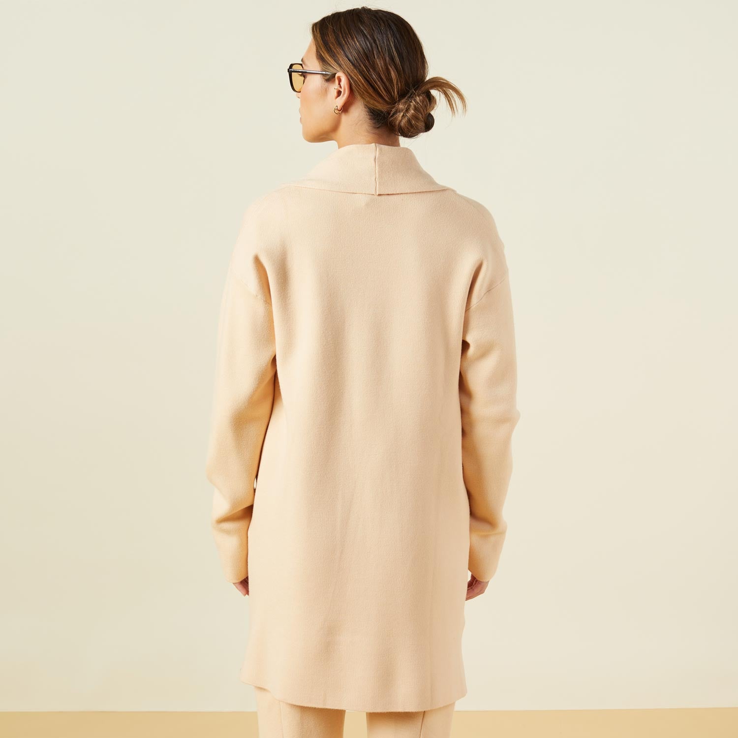 Back view of model wearing the supersoft sweater knit cardigan in vanilla.