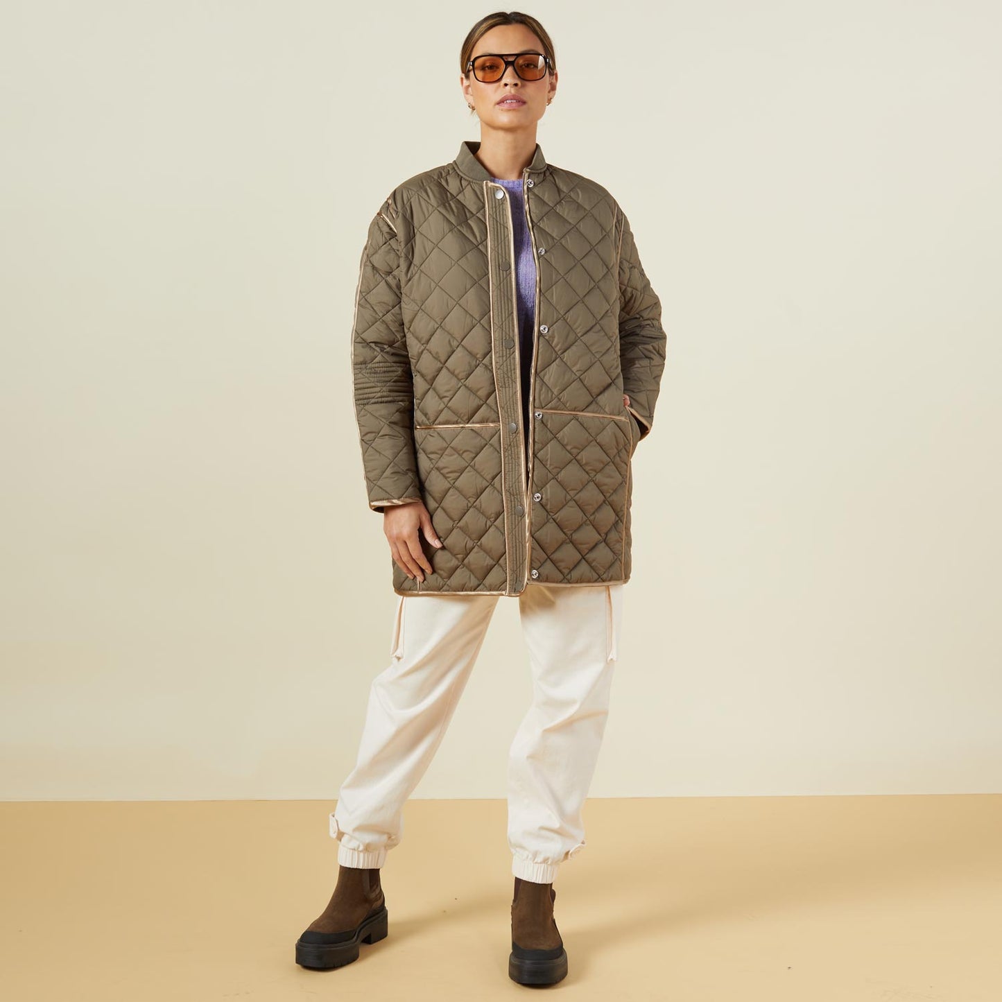 Front view of model wearing the quilted bomber in laurel green.