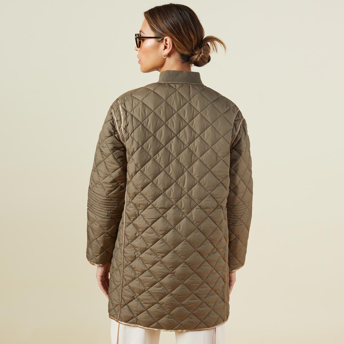 Back view of model wearing the quilted bomber in laurel green.