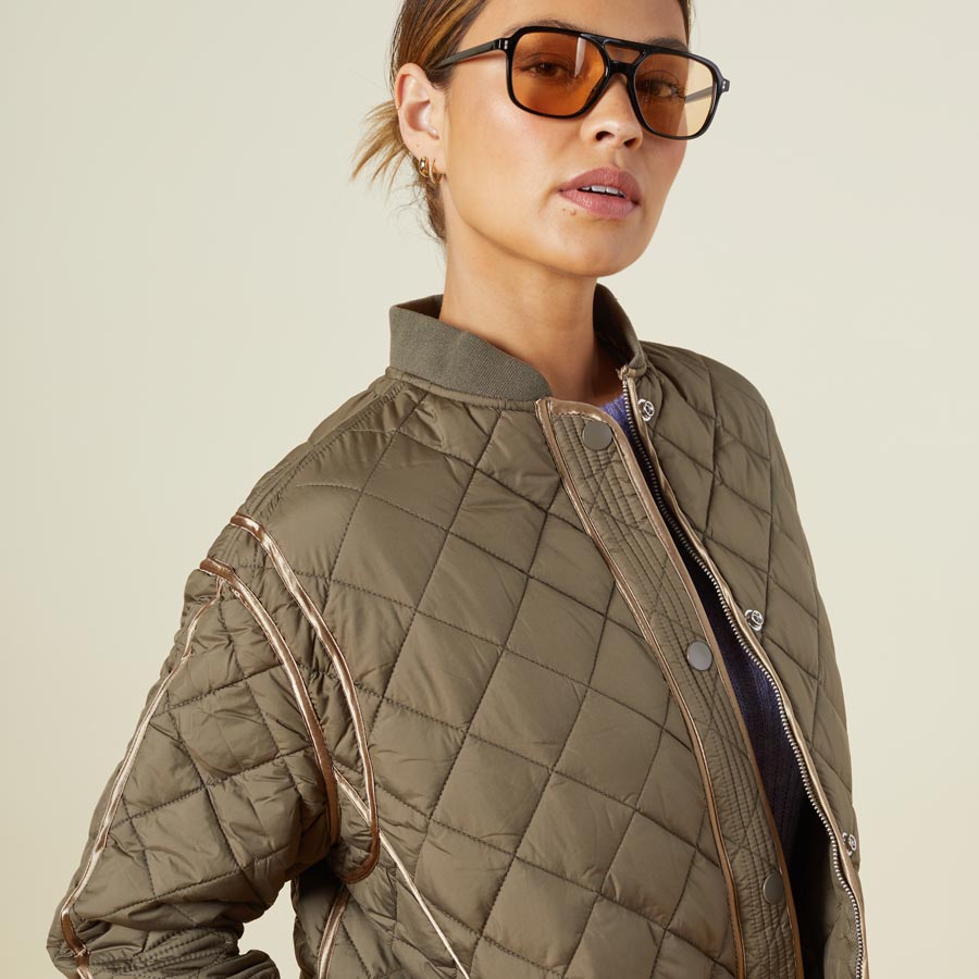 Close up view of model wearing the quilted bomber in laurel green.
