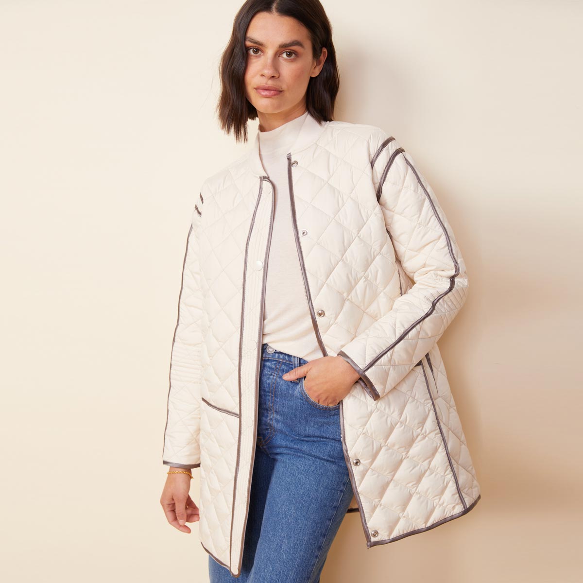 Front view of model wearing the quilted bomber in off white.