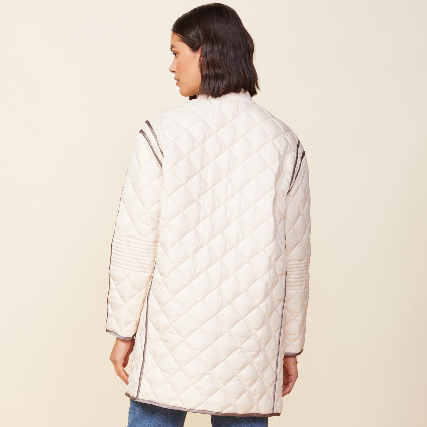Back view of model wearing the quilted bomber in off white.